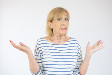 Middle age beautiful woman wearing casual t-shirt standing over isolated white background clueless and confused with open arms, no idea and doubtful face.