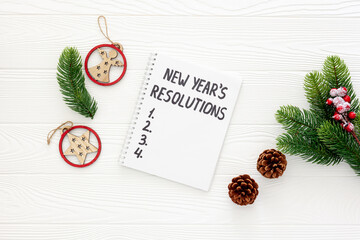New Year's resolutions with Christmas decorations on yellow flat lay