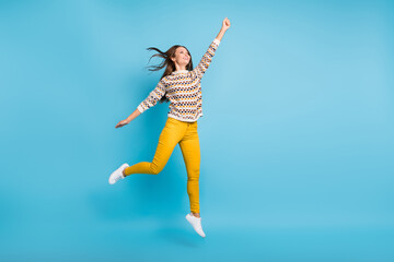 Full length photo of sweet woman dressed ornament pullover jumping empty space rising fist isolated blue color background
