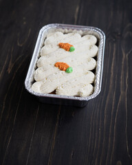 Carrot cake and cream cheese in an aluminium container. Wooden background.