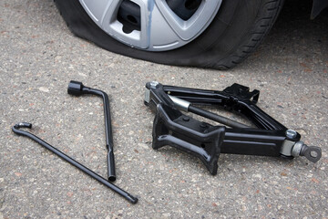 Flat tire of a car, wheel replacement tools, trouble on the road.