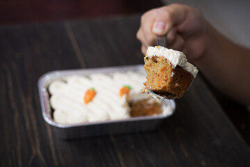 Carrot cake and cream cheese in an aluminium container. Wooden background.