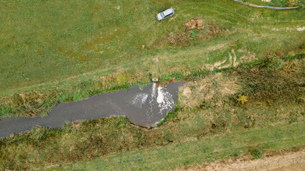 Aerial view of cement sewer pipe with water leaking into the river. Ecology problem concept.
