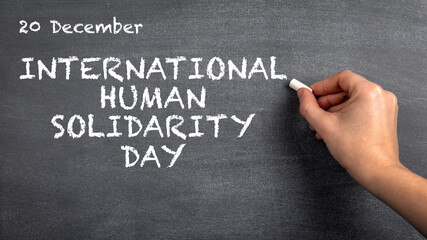 International Human Solidarity Day, 20 December. Woman's hand with white chalk