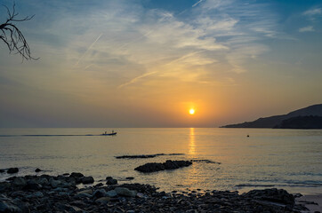 Fishermen in a motor boat going for work during sunrise on a beach in Muscat, Oman