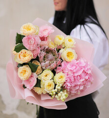 Flower shop. Beautiful bouquet of mixed flowers in woman's hands. the work of the florist at a flower shop. Delicate color. Fresh cut flower.