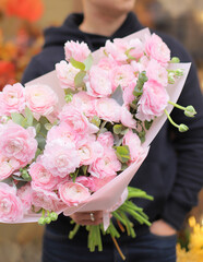 Young man florist holding big beautiful blossoming mono bouquet of pink ranunculus clooney hanoi flowers.