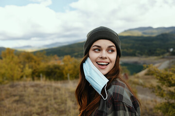 Energetic woman with a medical mask for a walk in nature in the autumn forest