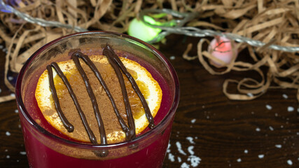 A glass of rose warming drink with a slice of orange, cinnamon and chocolate. Close-up.