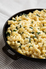 Homemade Spinach Mac and Cheese in a cast-iron pan on cloth, side view. Close-up.