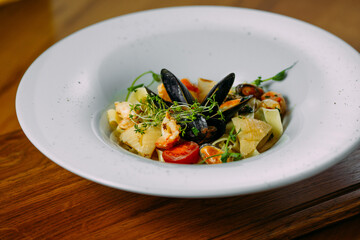 pasta with seafood in a white plate on a wooden table