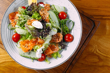 
italian vegetarian salmon salad cucumber vegetables on plate and wood