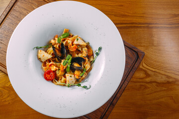 
pasta with seafood in a white plate on a wooden table