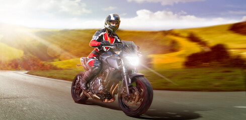female motorcyclist riding motorbike on the country road accelerating while leaving the curve to overtake. motion blurring rural country side background. copy space to the right for your advertisement