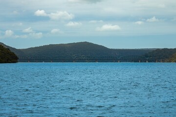 Steel Railway Bridge on Hawkesbury River on Sydney Central Coast NSW Australia with green lush mountains in background