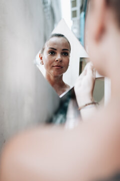 Short-haired woman looking in a mirrow at herself