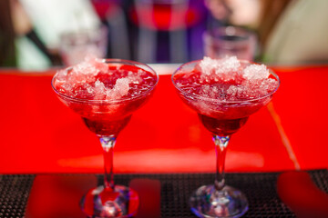 To red cocktails on a bar counter
