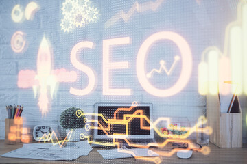 Double exposure of table with computer and seo drawing hologram. Search optimization concept.