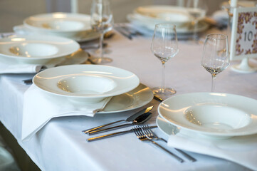Close up details of a plate, cutlery and empty wine glasses