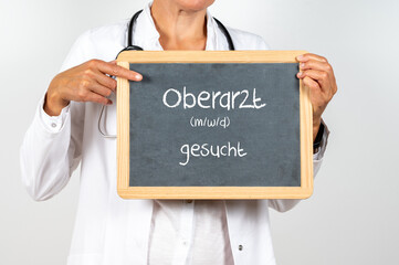 Ärztin mit einer Tafel Oberarzt gesucht als Stellen Anzeige