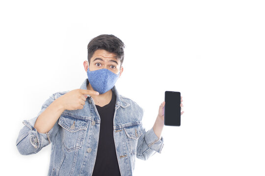 Caucasian Man Wearing A Blue Mask Pointing To His Phone With A Surprised Face