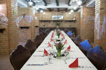 Big table with wooden chairs , inside a restaurant prepared for the wedding guests.