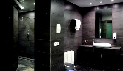 Interior of a bathroom with hand dryers and showers on the wall