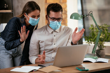 Businessman and businesswoman with medical mask in office. Colleagues working together. COVID - 19 virus protection