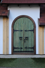 Wooden double barn door with rounded corners. Wooden plank door with forged metal parts.