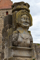 The bust of the famous Dame Carcass (reproduction of the original statue) and Narbonne tower. The legend of Lady Carcas is an etiological story about the origin of Carcassonne's name, France.