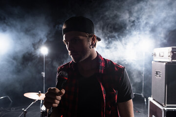 Rock band vocalist holding microphone, with smoke and backlit on blurred background