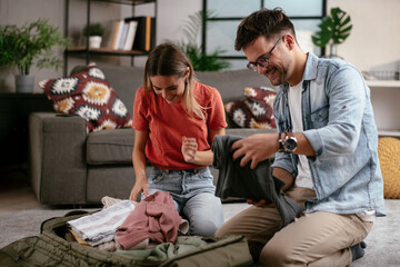 Loving couple packing clothes into travel bag. Boyfriend and girlfriend preparing for the trip.