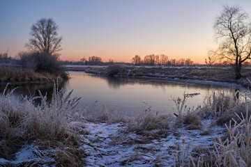 Breath of winter, first ice on the lake, dawn on a frosty morning with frost on the grass, close-up of frost, patterns on the first ice.