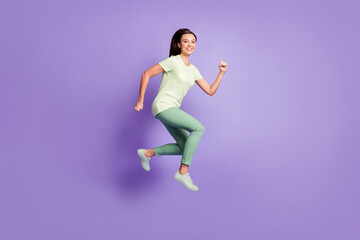 Fototapeta na wymiar Full size profile photo of adorable cheerful lady run jump wear light green isolated on violet color background