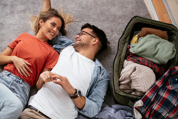 Obraz premium Loving couple packing clothes into travel bag. Boyfriend and girlfriend preparing for the trip.