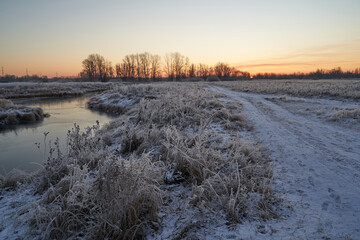 Breath of winter, first ice on the lake, dawn on a frosty morning with frost on the grass, close-up of frost, patterns on the first ice.