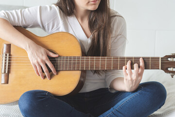 Woman playing her guitar at home, detail shot, no face