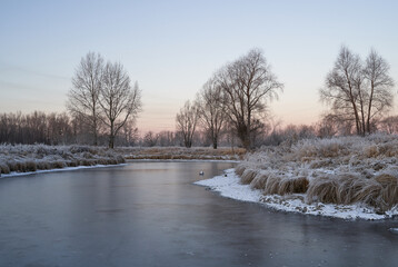 Breath of winter, first ice on the lake, dawn on a frosty morning with frost on the grass, close-up...