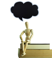 Wooden dummy sitting on a pile of books and a textbook space over his head as if he were thinking about it. All on a white background