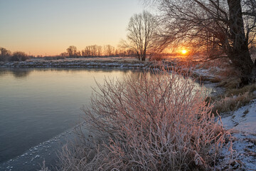 Breath of winter, first ice on the lake, dawn on a frosty morning with frost on the grass, close-up of frost, patterns on the first ice.