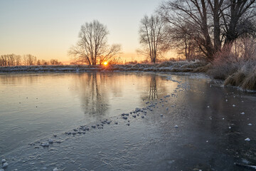 Breath of winter, first ice on the lake, dawn on a frosty morning with frost on the grass, close-up of frost, patterns on the first ice.