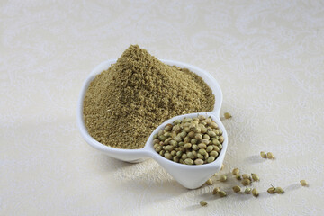 Coriander seeds and powder in a white ceramic bowl