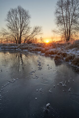 Breath of winter, first ice on the lake, dawn on a frosty morning with frost on the grass, close-up of frost, patterns on the first ice.