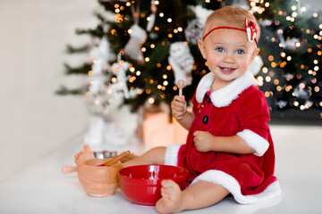 baby girl sitting at the Cristmas table on the background of a Christmas tree