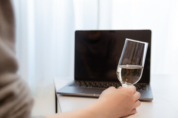 パソコンの前で飲み物を飲む。家でリモート・オンライン飲み、おうち時間。