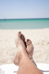 close-up of a man's legs lying on a chaise longue against the background of azure sea water, vacation at sea.