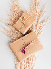 Zero waste holiday gifts wrapped in plastic free paper with dried floral decor on gray background.