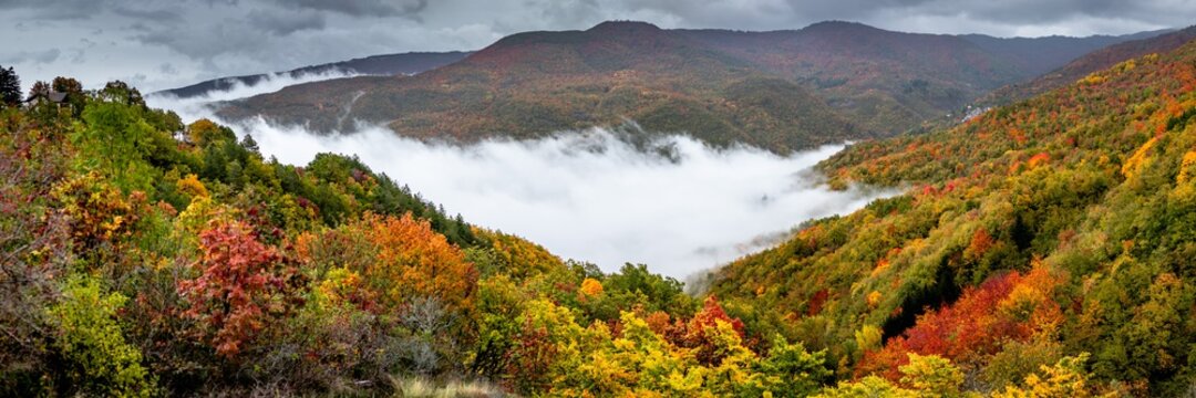 Panorama of foggy autumn landscape in the mountains with colored trees in Caldirola, Italy