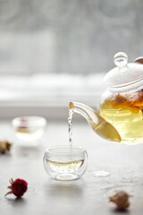 A delicious herbal tea from rose petals, cozy atmosphere. White floral drink in a transparent glass. Flowing liquid.