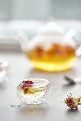 A delicious herbal tea from rose petals, cozy atmosphere. White floral drink in a transparent glass. Flowing liquid.